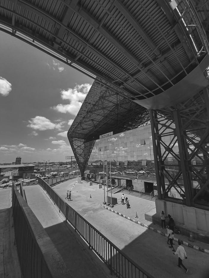 Black and white image of urban architecture in Lagos with people walking under viaduct.