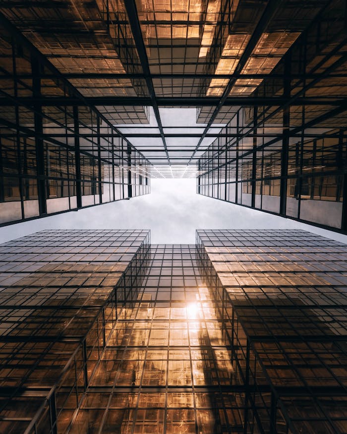 A stunning low-angle shot of modern skyscrapers in Hong Kong with reflective glass and a bright sky.