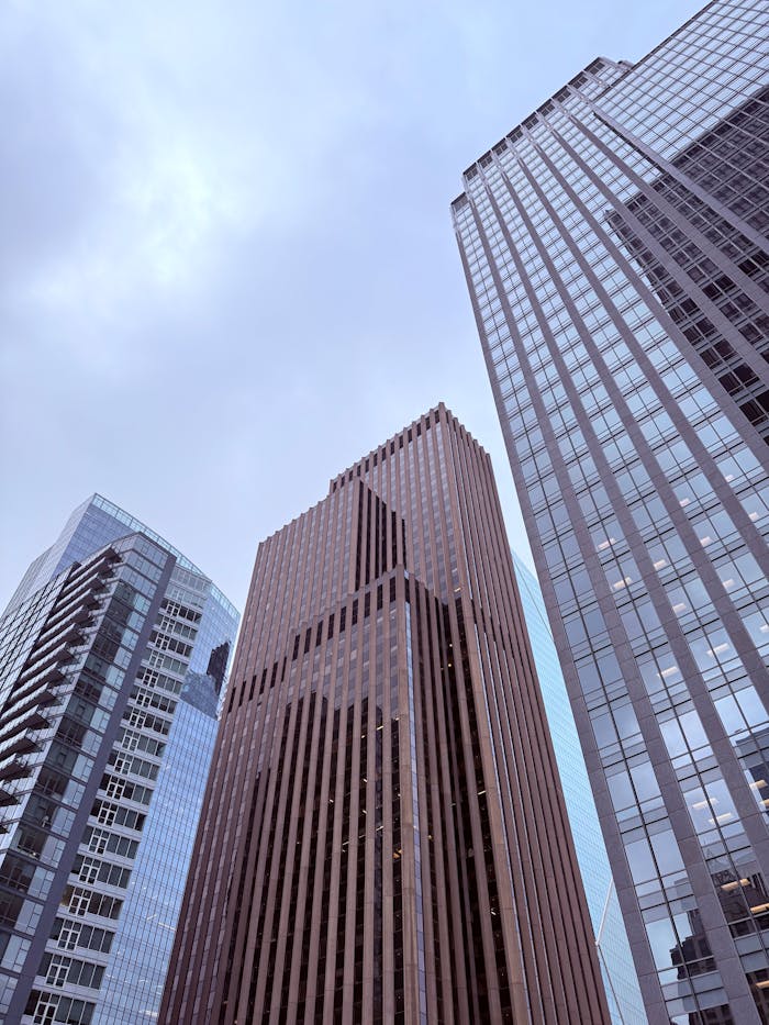 Tall modern skyscrapers reaching into a cloudy sky in a bustling city center.