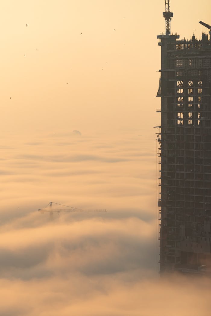 Dramatic view of a skyscraper emerging from thick fog in Dubai at dawn, showcasing urban growth.